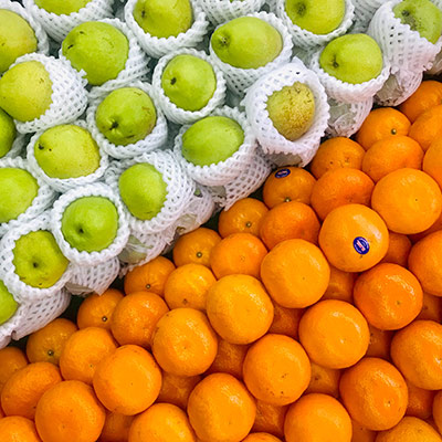 A stack of oranges next to a stack of apples