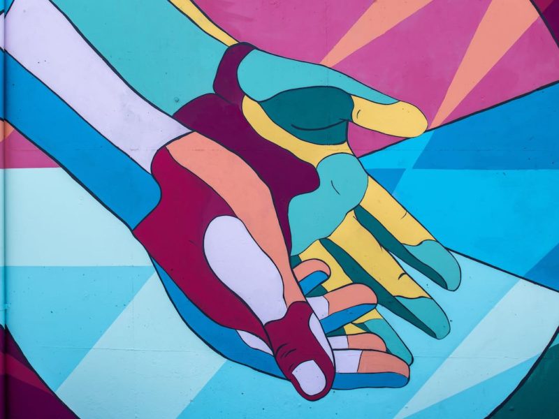 Photo by Tim Mossholder of a mural of brightly colored hands joined and reaching down.