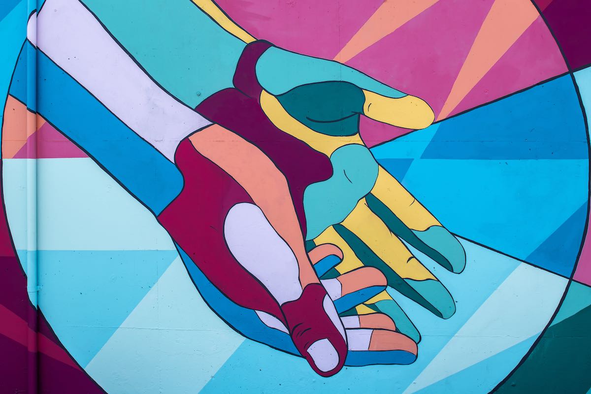 Photo by Tim Mossholder of a mural of brightly colored hands joined and reaching down.